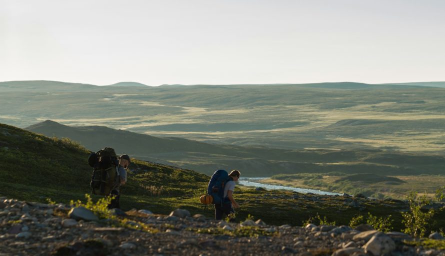 Folk på fjelltur med store sekker på ryggen i åpent terreng. Ved å ta med alt avfall man ikke kan brenne hjemme igjen blir turen helt avfallsfri